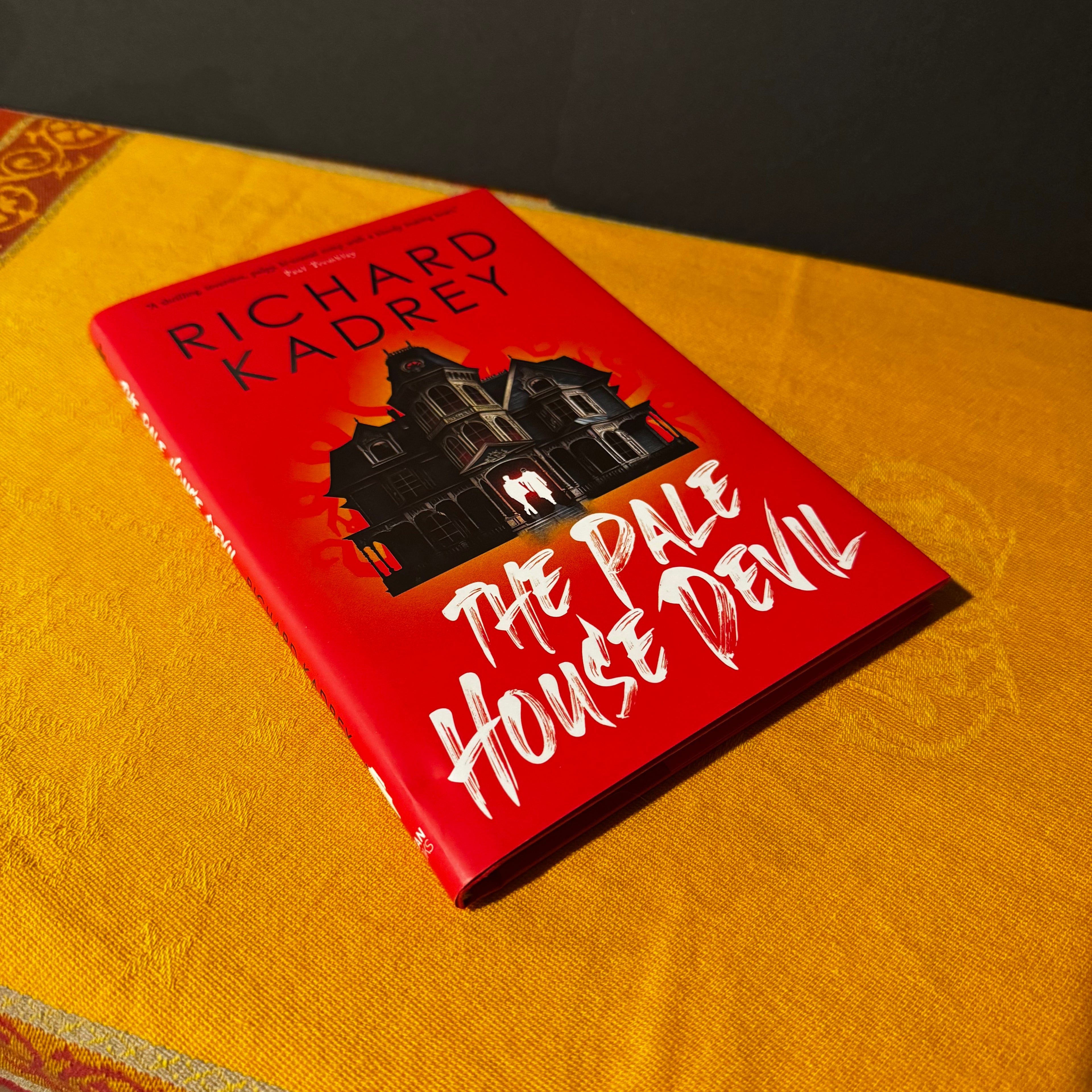 Book titled 'The Pale House Devil' by Richard Kadrey on a yellow surface