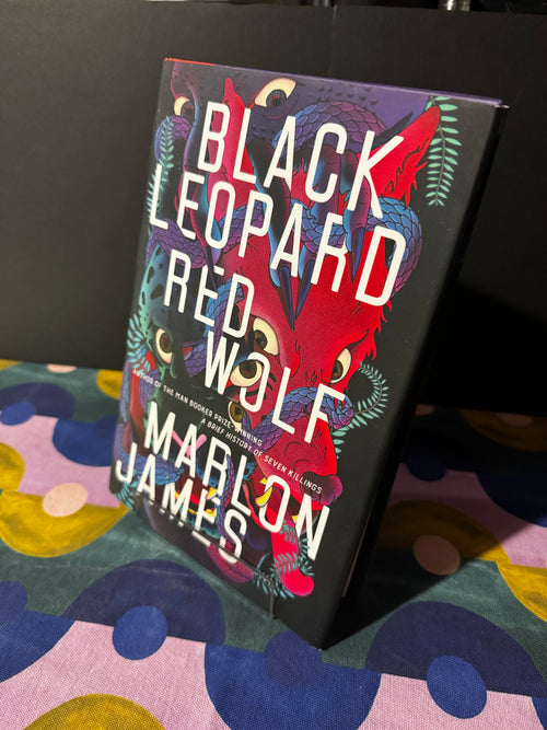 Book titled 'Black Leopard, Red Wolf' by Marlon James on a colorful fabric background