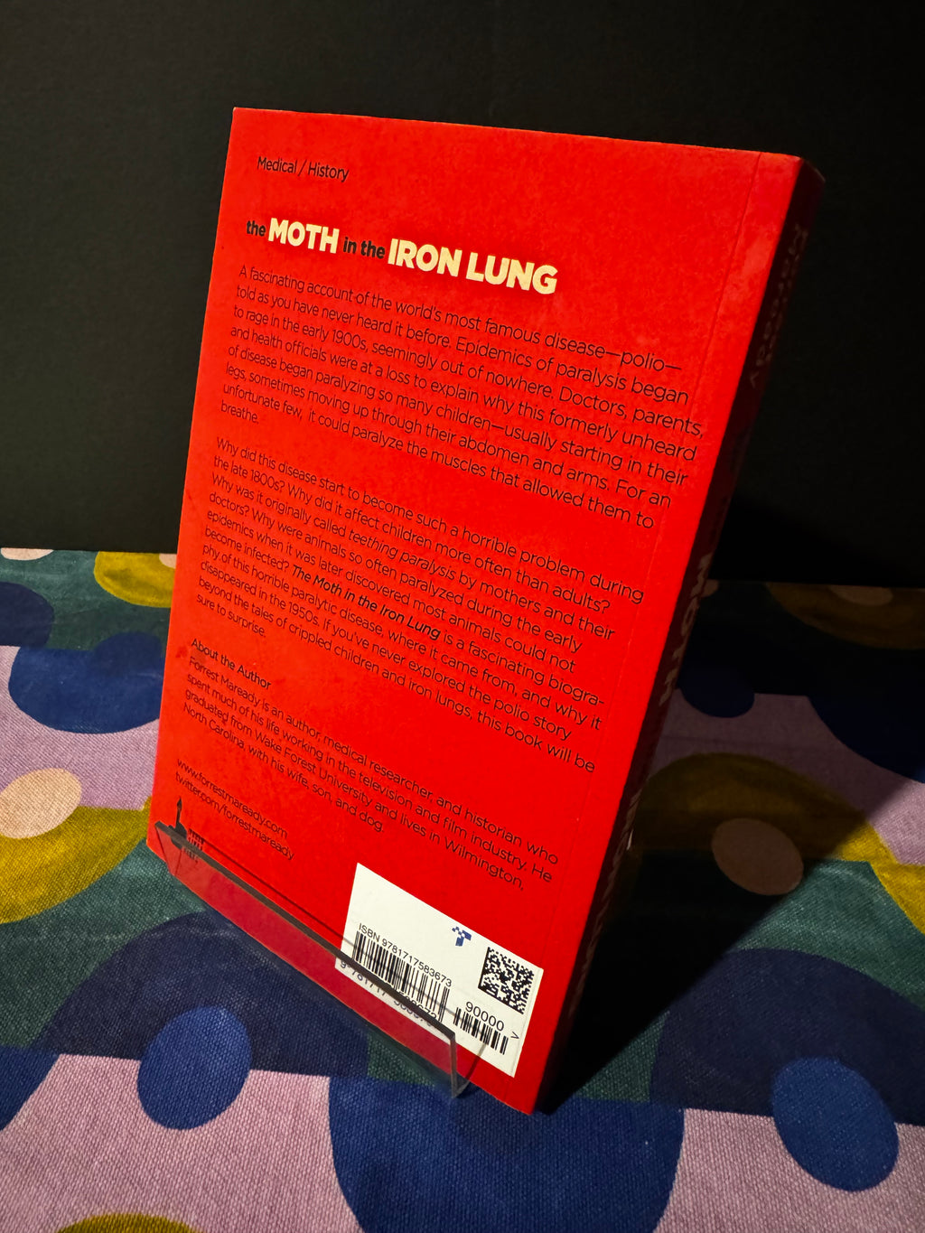 Red book cover with text and a barcode on a colorful fabric background