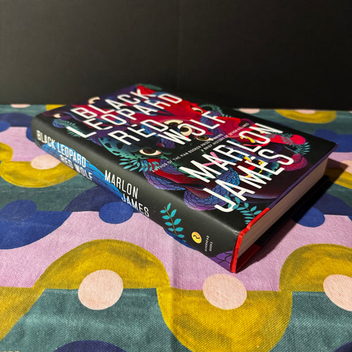Book titled 'Black Leopard, Red Wolf' by Marlon James on a colorful fabric background