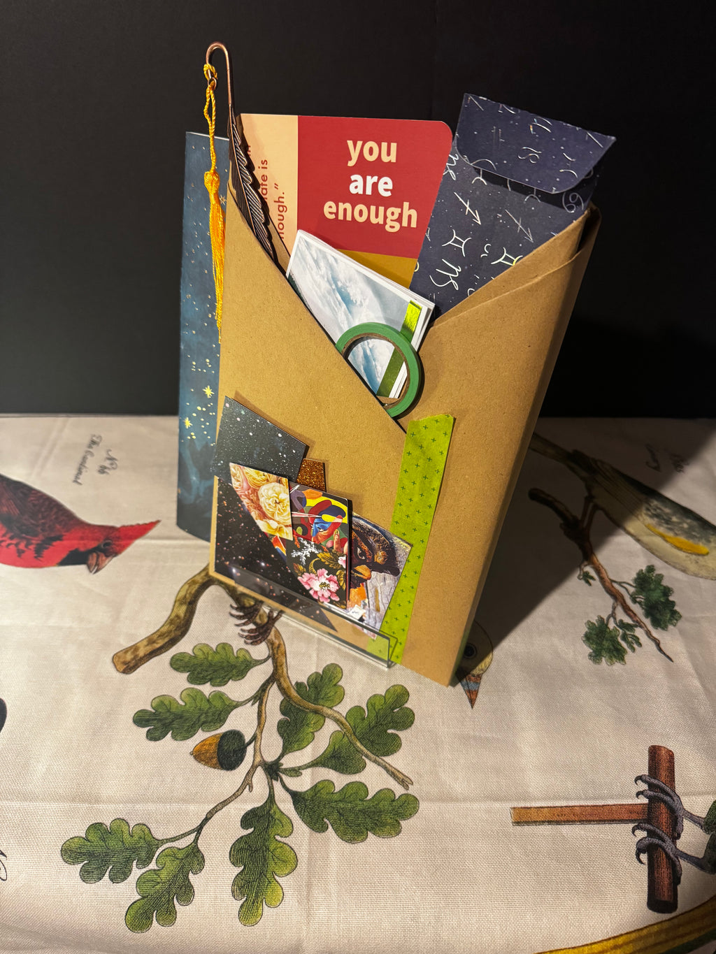 Book with various items including a card that says 'you are enough' on a patterned surface.