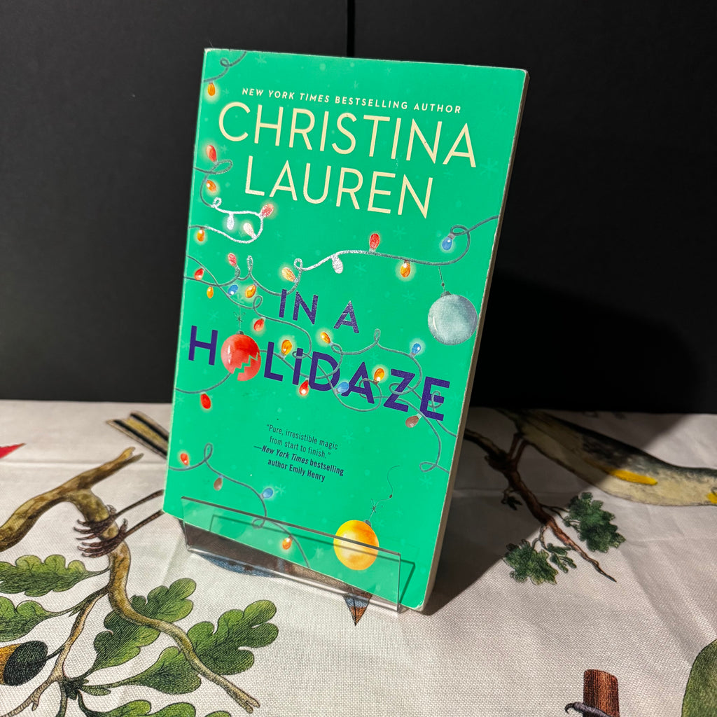 Book titled 'In a Holidaze' by Christina Lauren on a decorative surface with a dark background