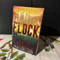 Book titled 'Flock' by Kate Stewart on a table with a dark background