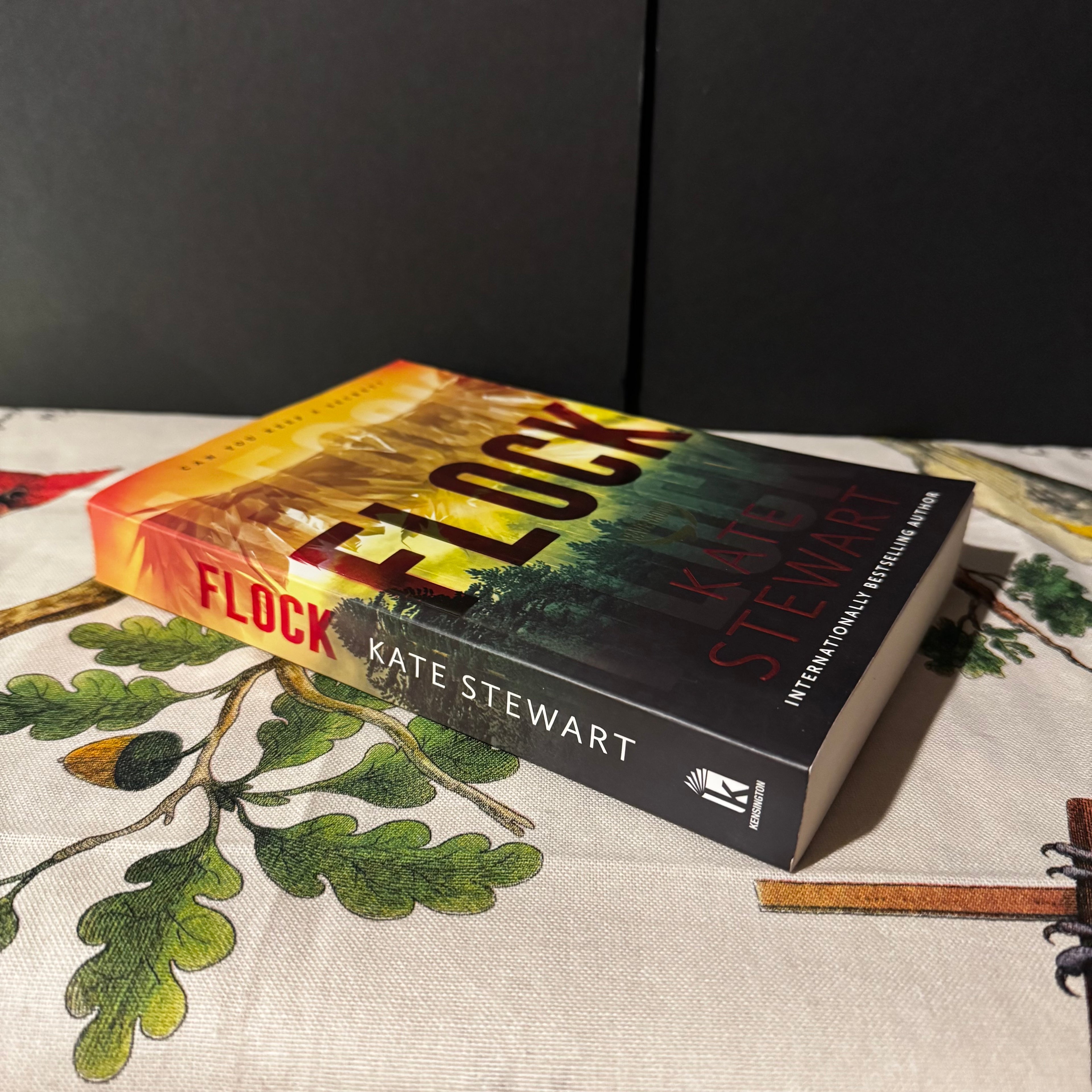 Book titled 'Flock' by Kate Stewart on a surface with leaf patterns
