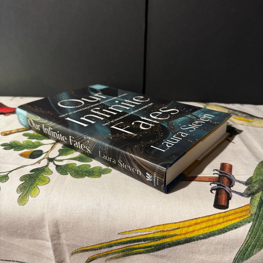 Book titled 'Our Infinite Fates' by Laura Steven on a decorative surface with floral patterns.