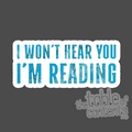 Sticker with text 'I won't hear you I'm reading' on a dark background