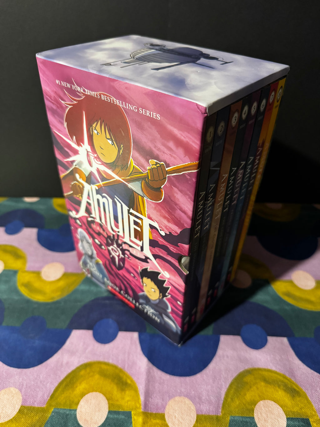 Collection of 'Amulet' books stacked on a colorful surface