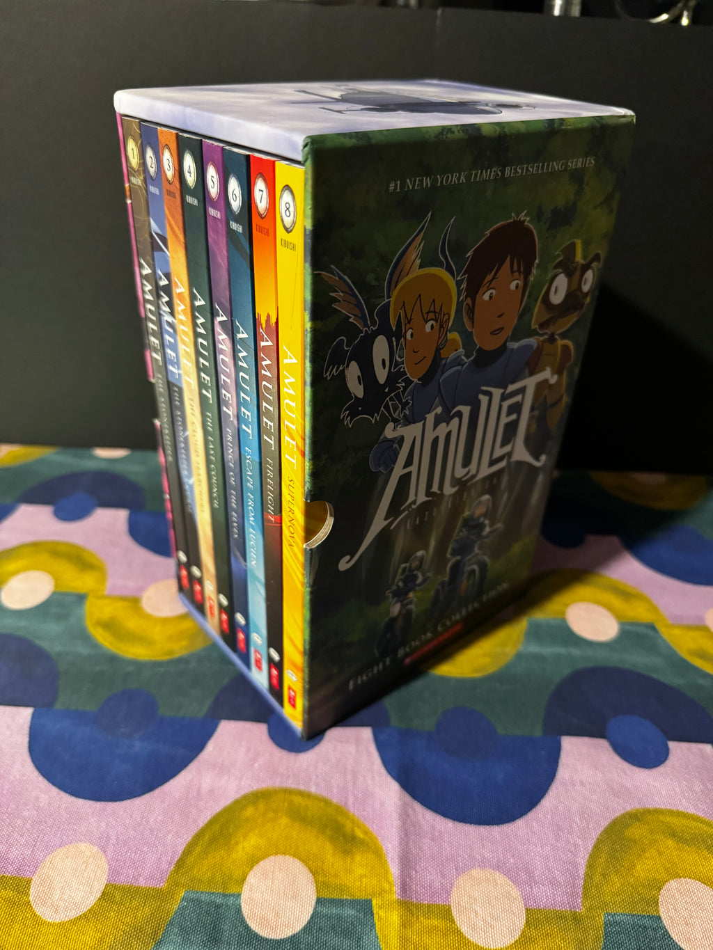 Stack of books titled 'Amulet' on a colorful surface