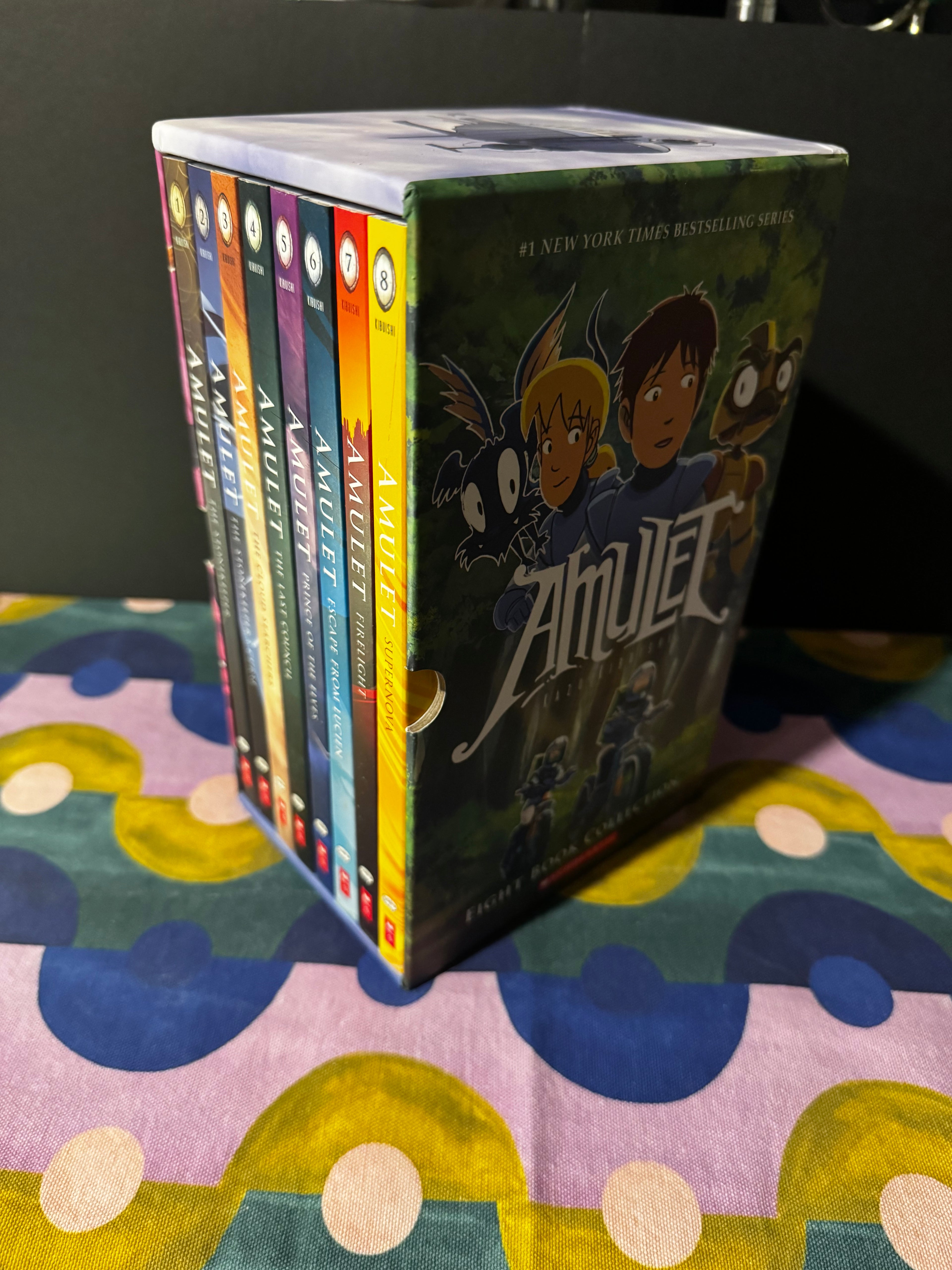 Stack of books titled 'Amulet' on a colorful surface