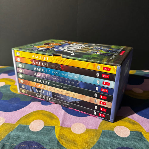 Collection of 'Amulet' books stacked on a colorful surface with a dark background