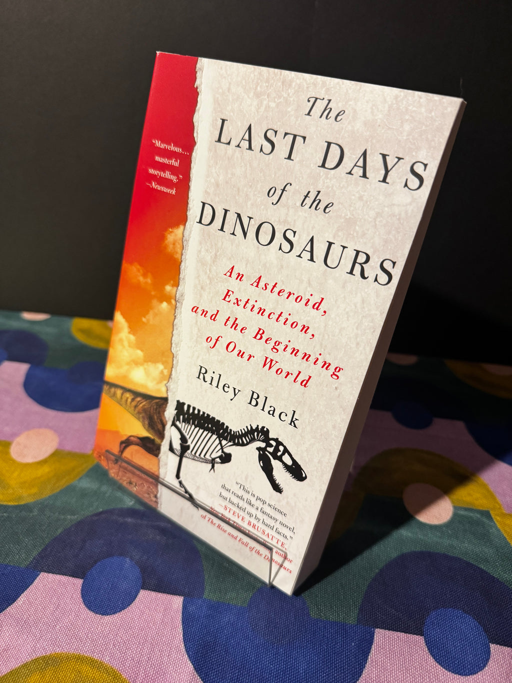 Book titled 'The Last Days of the Dinosaurs' on a colorful fabric background