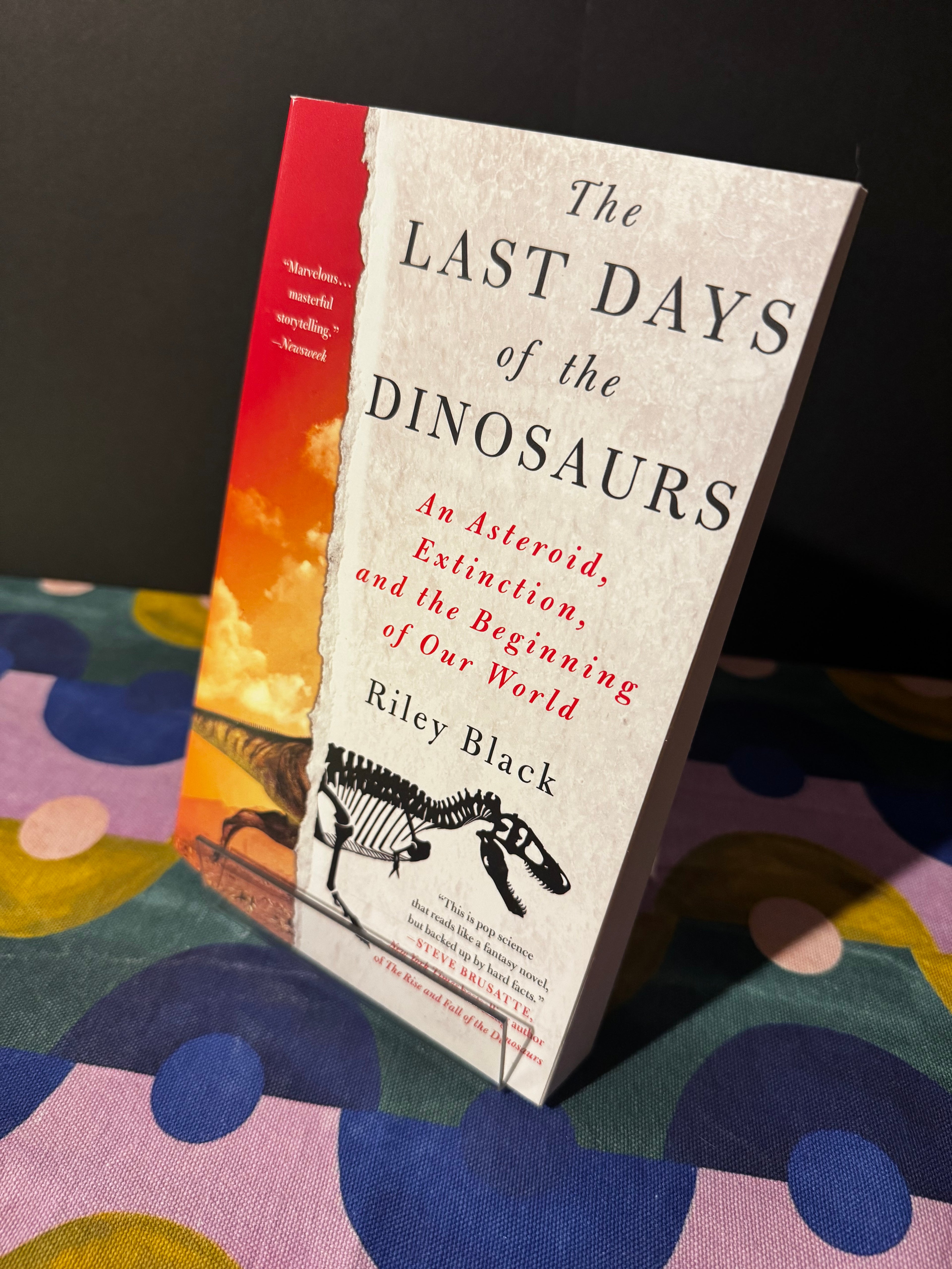 Book titled 'The Last Days of the Dinosaurs' on a colorful fabric background