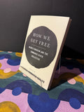 Book titled 'How We Get Free' on a colorful fabric background