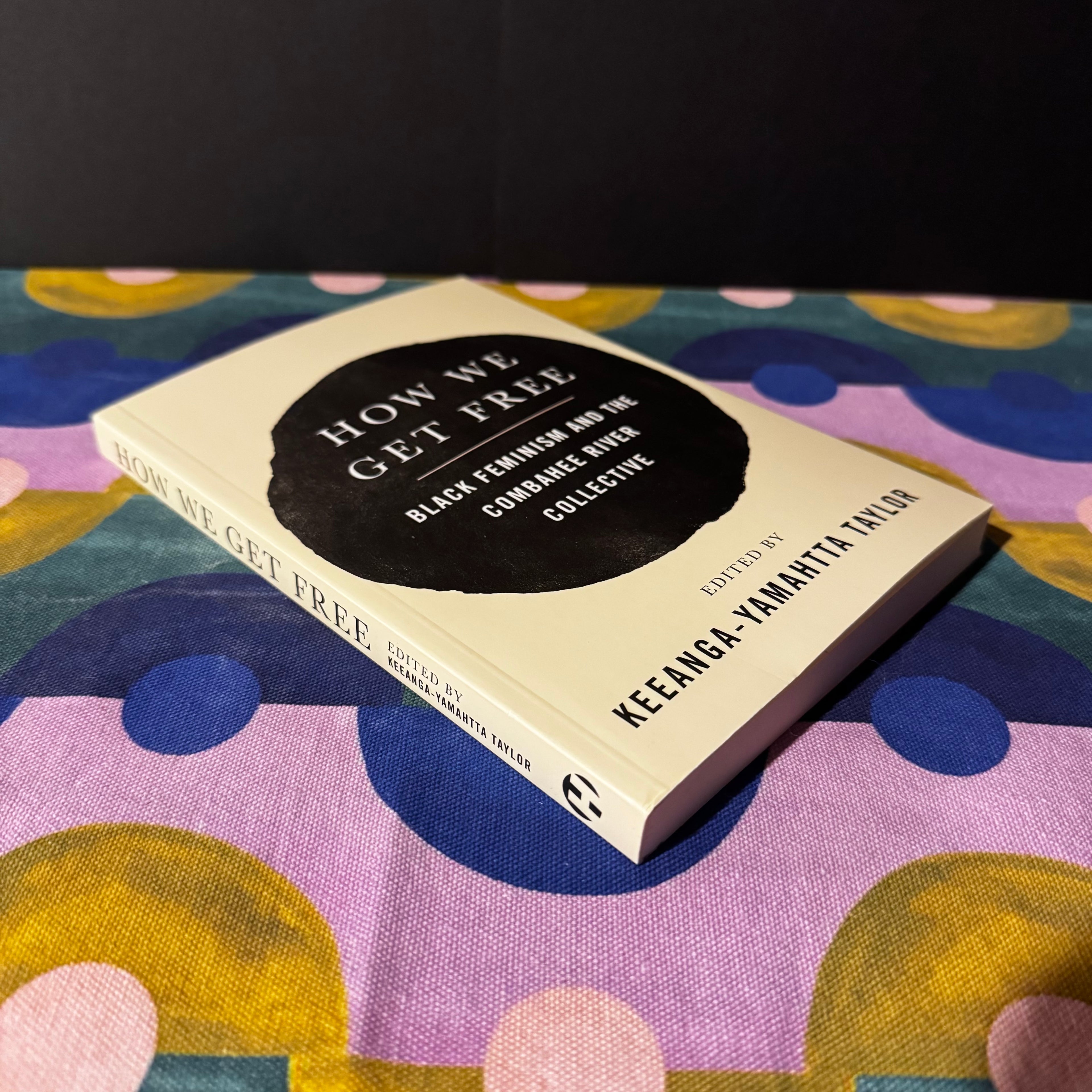 Book titled 'How We Get Free' on a colorful fabric background