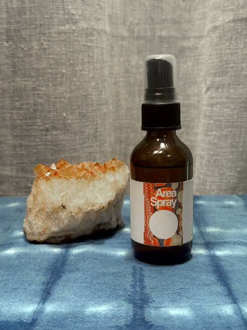 Bottle of 'Area Spray' with a crystal on a textured surface