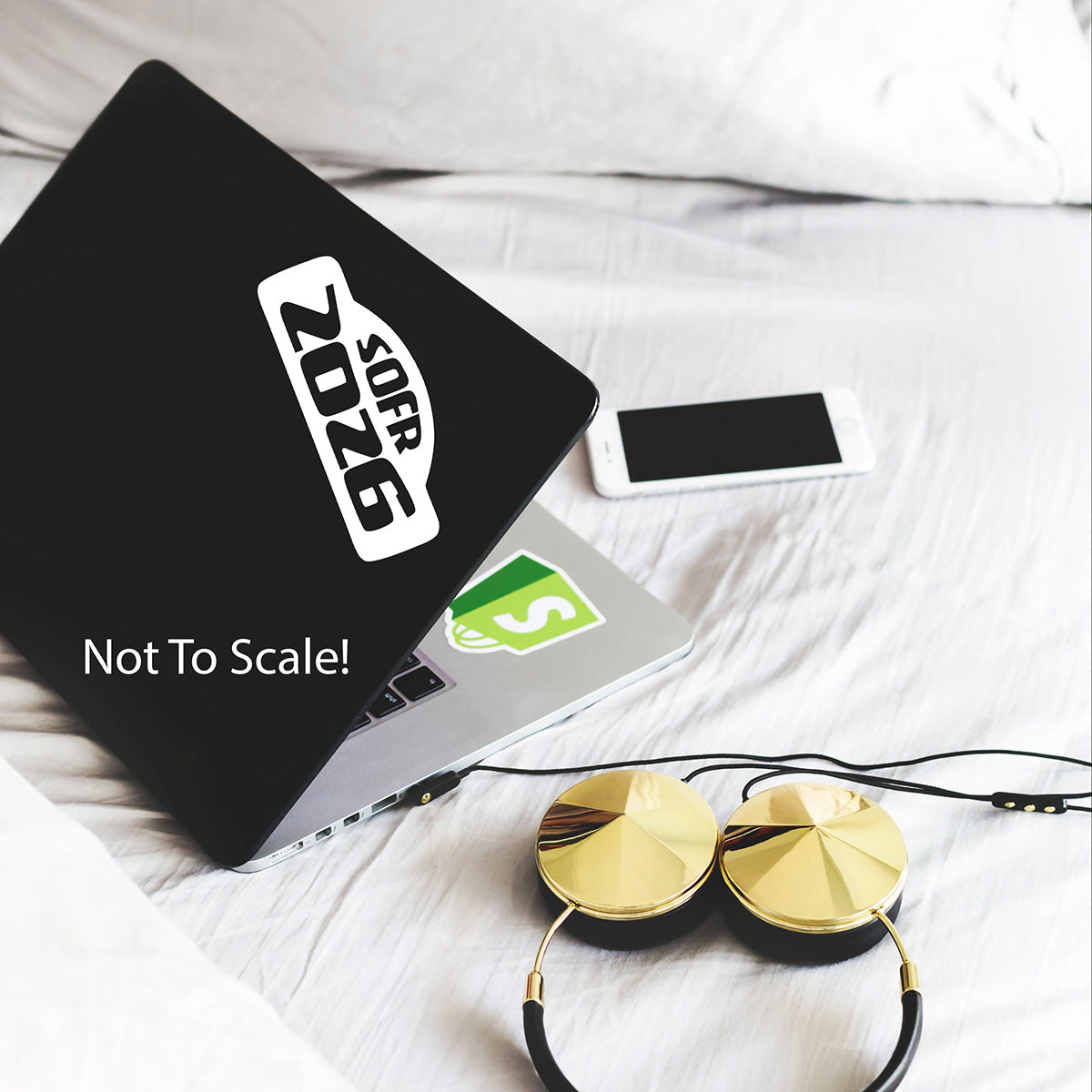 Black laptop with a sticker on a white surface with headphones and a phone.