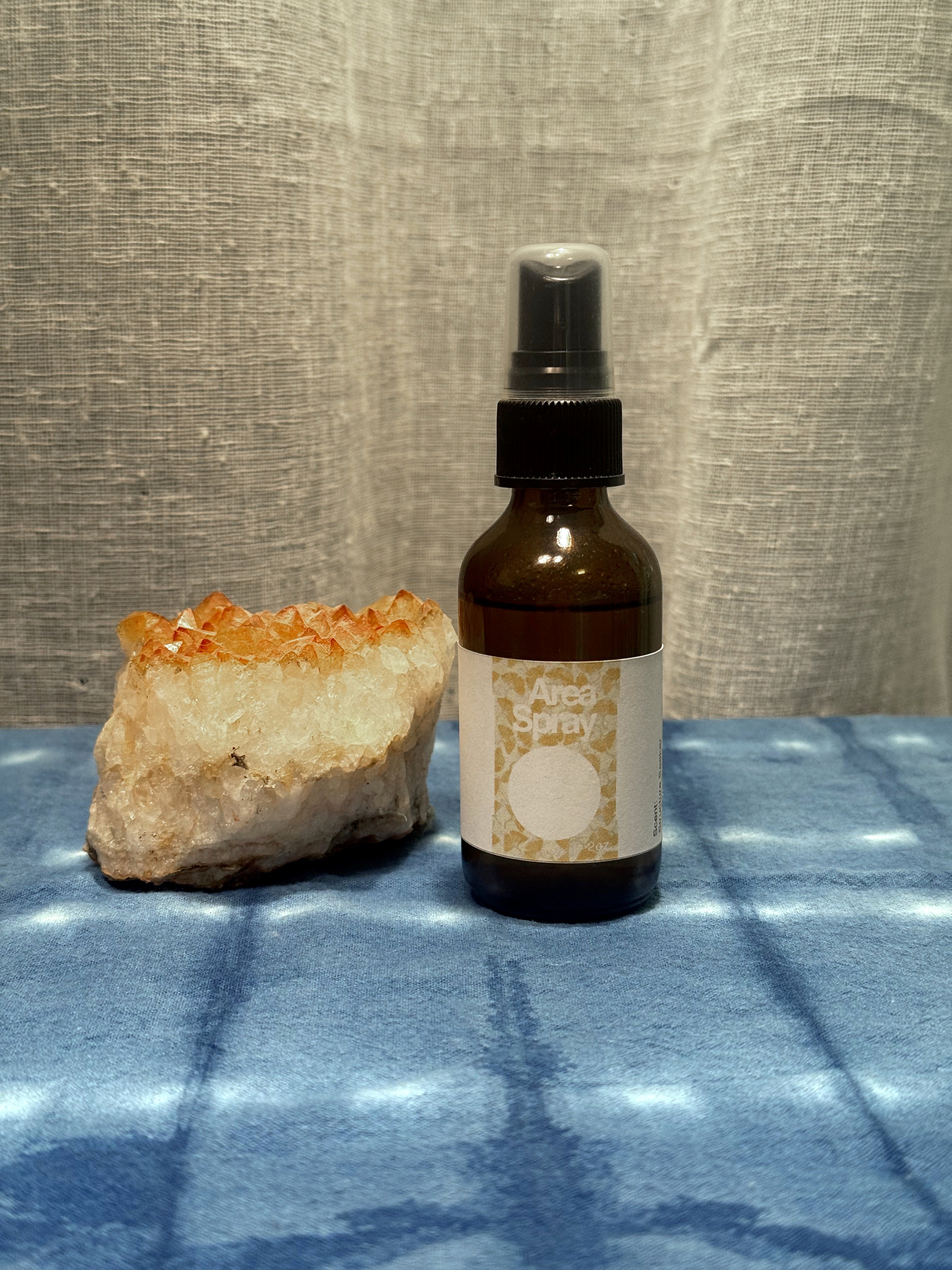 Brown spray bottle with label next to a crystal on a textured surface